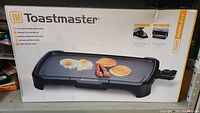 Box of Toastmaster electric griddle showing the brand, product image, and features like nonstick ceramic surface and adjustable temperature control.