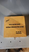 Wooden storage box labeled Nobel Wood Carving Knife with product details.