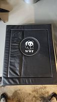 Black binder with WWF logo embossed on the front cover, indicating the collection's theme and branding.