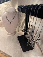 Photo of 11 vintage necklaces arranged on a stand and display bust showing the variety of designs and pendants.