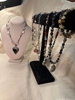 Seven vintage polished stone jewelry pieces displayed on necklace stand and bracelet holder, focusing on arrangement and colors.