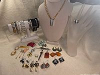 Photo showing entire assortment of vintage costume jewelry including bracelets, necklace, ring, earrings, and pins laid out on fabric with display stands