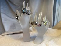 Full view of six vintage cocktail rings displayed on frosted hand mannequins showing styles and color variety.