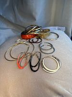 Photo showing 6 pairs of vintage hoop earrings and 5 bangles including orange enamel and metal bangles, various hoop styles.