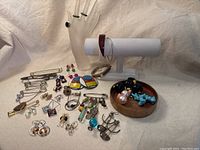Full grouping of over 20 vintage retro style jewelry items including earrings, rings, pins, brooches, and bracelets displayed on cloth with a hand mannequin and jewelry display stand
