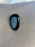 Top view of the cocktail ring showing the smooth, polished black natural stone on an adjustable silver band.