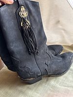 Left side view of a black vintage Zodiac leather and suede boot, showing the metal embellishments and tassels on the upper portion with some surface wear.