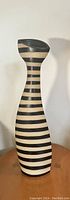 Full front view of tall ceramic vase with modern black and cream stripes on wooden surface