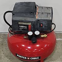Front view showing the red tank with Porter Cable logo, black motor housing with pressure gauges and power switch.