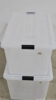 Two stacked clear plastic storage totes with lids, showing size and latch detail.