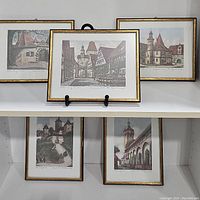 Group view of all five framed colored etchings displayed on shelf