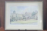 Framed colored print showing the Earl of Leicester's Hospital in Warwick with gardens, in a brown wooden frame and cream matting.