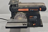 Front angle view of the WEN belt and disc sander showing the sanding belt and disc area with work table and power switch.