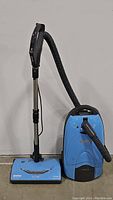 Full view of Kenmore light blue canister vacuum cleaner with attached hose, telescoping wand, and floor brush.