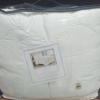 Packed white king size comforter in plastic wrapping showing label with product details and image of bed with comforter set.