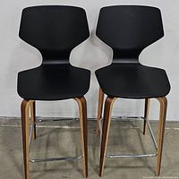 Pair of two black counter stools side-by-side against wall, showing full height, seat design, and leg construction