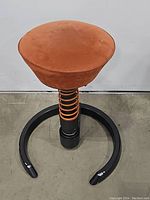 Full front view of orange seat, black base and coil spring