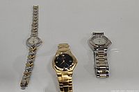 Three women's wristwatches with metal bracelets in assorted styles placed side by side on white background.