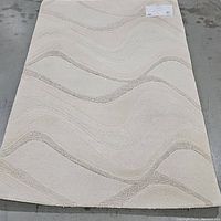 Full view of taupe and beige wool rug laid flat on floor showing wave pattern and overall size.