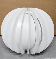Front view of the white plastic lamp shade showing the vertical slit design and spherical form.