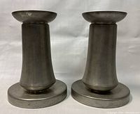 Front and side view of the two pewter candle holders, showing their shape and condition.