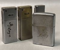Four lighters standing upright showing front profiles: two ribbed slims, one smooth slim, one flip-top Zippo