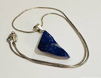 Necklace with polished triangular lapis pendant on a sterling silver chain, showing front view of pendant and chain clasp.