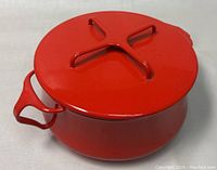 Top view of the red enamel pot with lid closed, showing lid handle and pot handles.