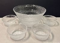 Five-piece clear textured glass bowl set arranged showing large bowl in center with four smaller bowls around it.