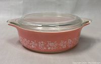 Front angle view of pink Gooseberry Pyrex casserole dish with lid showing pattern and handles.