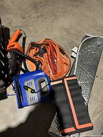 Full view of the lot including 12V vacuum cleaner, booster cables, air pump, sun shade, and safety kit bag