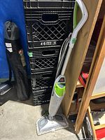 Full view of the Bissell PowerFresh steam mop leaning against black crates and wood shelving.