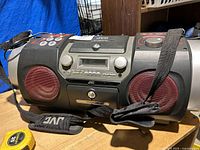 Front view of JVC RV-NB200 boombox showing speakers, control knobs, buttons, and cassette door.
