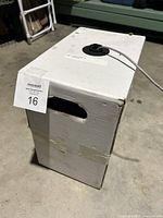 White cardboard box with black spool, visible gray cable extending from the box, label on top shows product info.