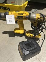 Photo showing DeWalt cordless drill, impact driver, and battery charger together on concrete floor.