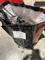 View inside the Metro bag showing assorted hardware items including orange utility knives, pressure gauge, flexible metal hose, and small hardware accessories.