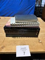 Photo showing six stacked notebooks and journals of various sizes and binding types on a wooden surface.