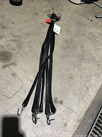 Six black rubber tie straps gathered and hanging, showing the metal hooks on each end.