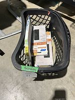 Black basket containing multiple open boxes of sandpaper sheets including Norton ProSand and Walisand brands, with labels showing grits and preparation types.