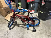 Full side view of the Spiderman bicycle showing the frame, tires, pedals, training wheels, and handlebar detail.
