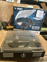 VIBE Sound USB turntable with closed dust cover and retail box in the background, placed on a patterned chair.