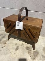 Closed vintage wooden sewing box, rectangular with angled stands and central wooden handle