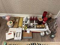 Full lot of candles and candle-related items arranged on floor against wall, showing a large variety including tapers, pillars, small figurines, and holders.