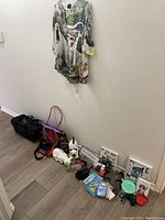 Cat-themed lot arranged on floor and wall, showing pet carrier, colorful tote, ceramic figures, books, signs, feeding dish.
