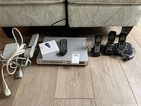 Wide view of all items on floor including DVD player, remote, Chromecast box, and Panasonic phone system with 3 handsets and base