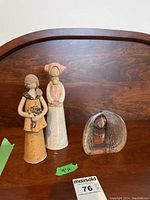 Two ceramic figurines and glass sculpture on wooden table