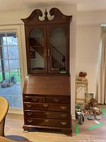 Front view of two-piece cherry wood secretary desk with closed drop-front and glass-door hutch.