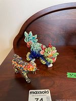 Photo showing both the colourful ceramic foo dog and the mosaic cat figure displayed together on a wooden surface