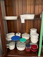 Wide view of food storage containers arranged on shelves including Corningware and glass/plastic storage pieces