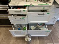 Kitchen drawers open showing contents of utensils and kitchen items.
